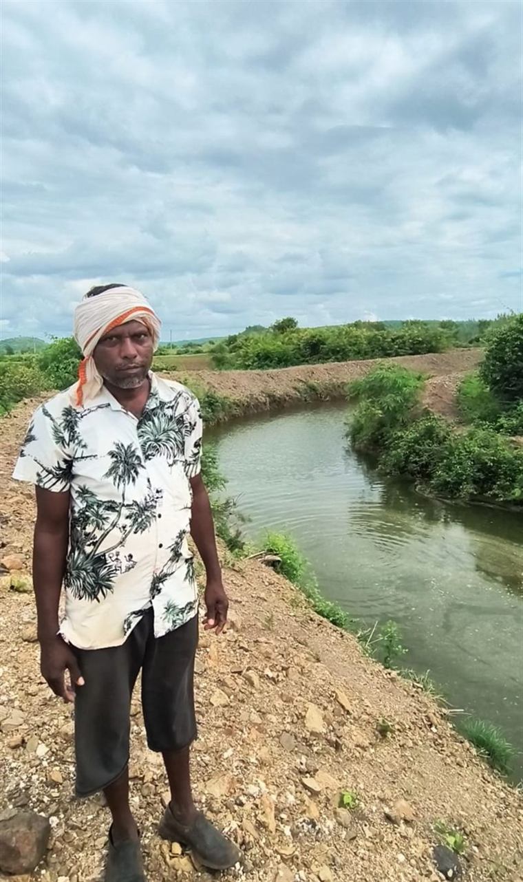 Khushal Devatale standing beside the Doha structure that irrigates his farm